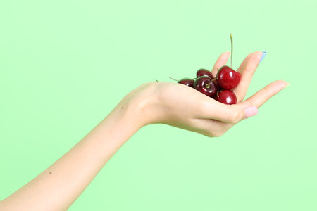 The Asian woman holding berry fruit in the hand on the yellow background.の写真素材
