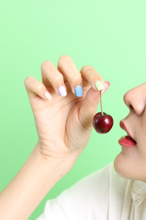 The Asian woman eating berry fruit in the hand on the yellow background.の写真素材