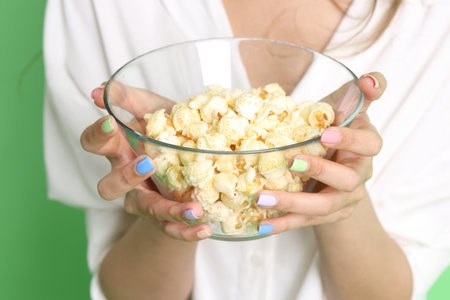 The Asian woman holding popcorn in the hand on the yellow background.の写真素材