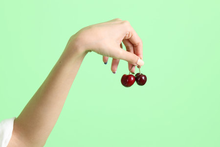 The Asian woman holding berry fruit in the hand on the yellow background.の写真素材