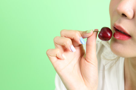 The Asian woman eating berry fruit in the hand on the yellow background.の写真素材