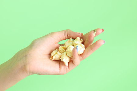 The Asian woman holding popcorn in the hand on the yellow background.の写真素材