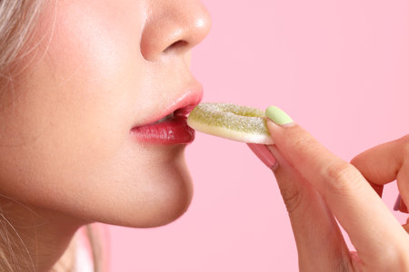 The Asian woman holding jelly in the hand on the pink background.の写真素材