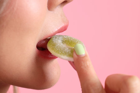 The Asian woman holding jelly in the hand on the pink background.