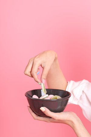 The Asian woman holding jelly in the hand on the pink background.の写真素材