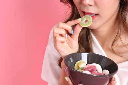 The Asian woman holding jelly in the hand on the pink background.の写真素材