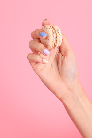 The Asian woman holding macaroons in the hand on the pink background.の写真素材