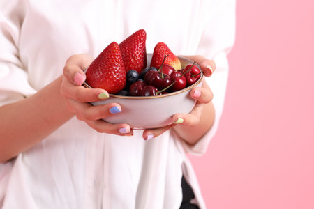 The Asian woman holding berry fruit in the hand on the pink background.の写真素材