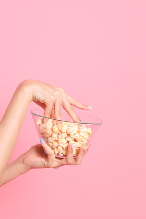 The Asian woman holding popcorn in the hand on the pink background.の写真素材