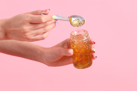 The Asian woman filling the orange jam to the sliced bread  in the pink background.の写真素材