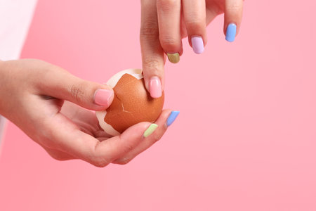 The Asian woman eating egg in the hand on the green background.