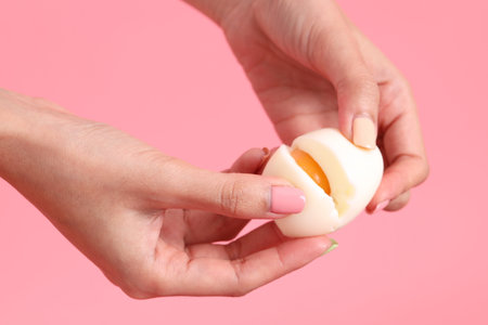 The Asian woman eating egg in the hand on the green background.の写真素材