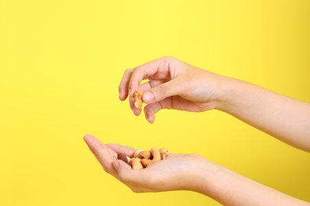 The Asian woman holding nuts on the yellow background.の写真素材