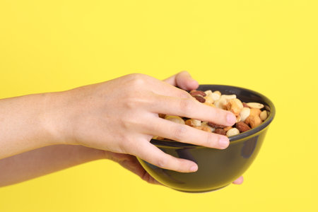 The Asian woman holding nuts on the yellow background.の写真素材