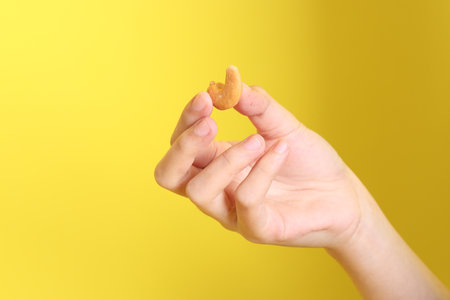 The Asian woman holding nuts on the yellow background.の写真素材