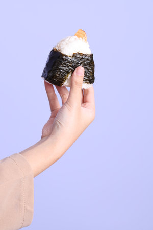The Asian woman holding onigiri on purplr background.の写真素材