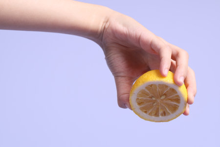 The Asian woman hand holding lemon in the purple background.の写真素材