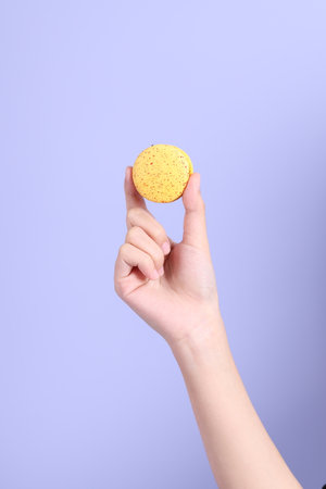 The Asian woman holding macaroon on the purple background.の写真素材