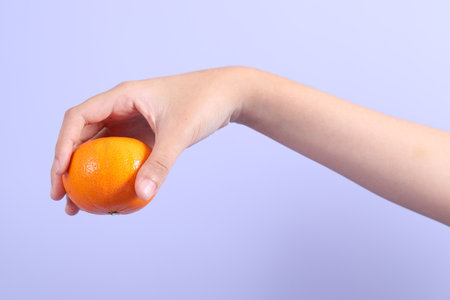 The Asian woman holding orange fruit on the purple background.の写真素材