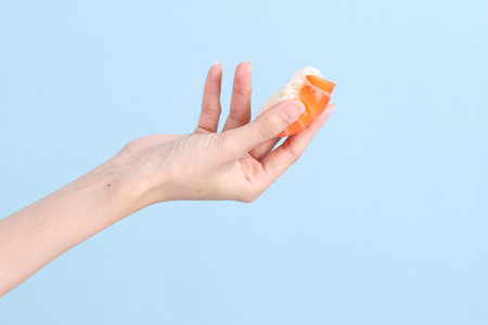 The Asian woman hand holding sushi in the blue background.の写真素材