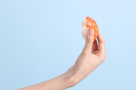 The Asian woman hand holding sushi in the blue background.の写真素材