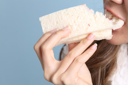 The Asian woman eating sandwiches on blue background.の写真素材