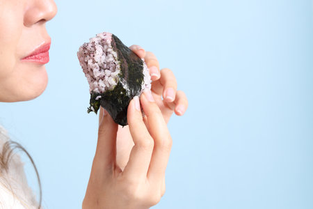 The Asian woman holding onigiri on blue background.の写真素材