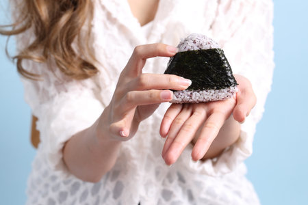The Asian woman holding onigiri on blue background.の写真素材