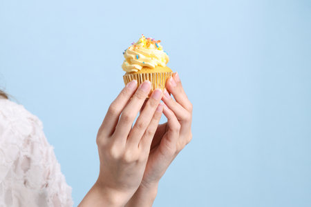 The Asian woman eating cupcakes on the blue background.の写真素材