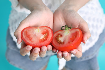 The Asian woman hand holding tomato in the green background.の写真素材