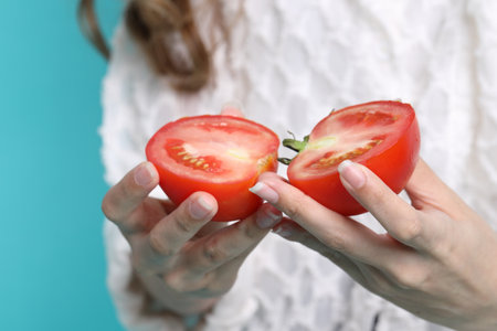 The Asian woman hand holding tomato in the green background.の写真素材