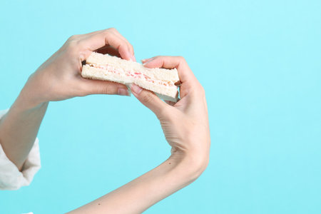 The Asian woman eating sandwiches on blue background.の写真素材