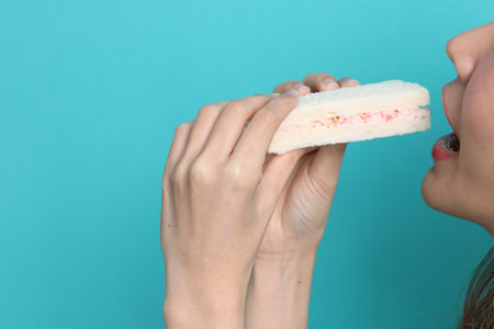 The Asian woman eating sandwiches on blue background.の写真素材