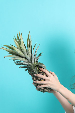 The Asian woman hand holding pineapple in the green background.の写真素材