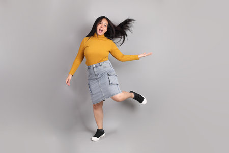 The full length of Southeast Asian woman standing on the grey background.の写真素材