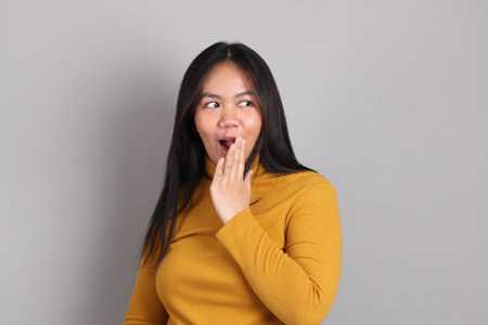 The adult Southeast Asian woman standing on the grey showing hand sign.の写真素材