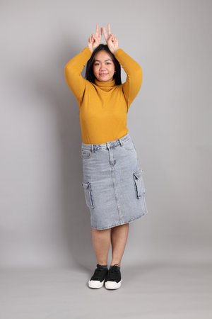 The full length of Southeast Asian woman standing on the grey background.の写真素材