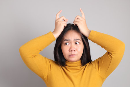 The adult Southeast Asian woman standing on the grey showing hand sign.