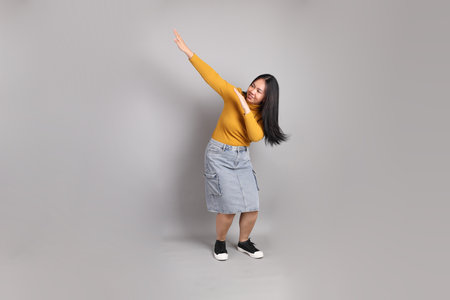The full length of Southeast Asian woman standing on the grey background.の写真素材