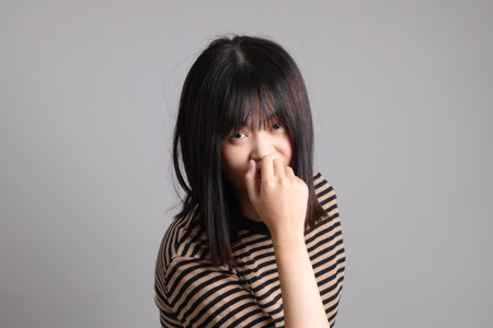 The young adult Asian woman standing on the grey backgroundの写真素材
