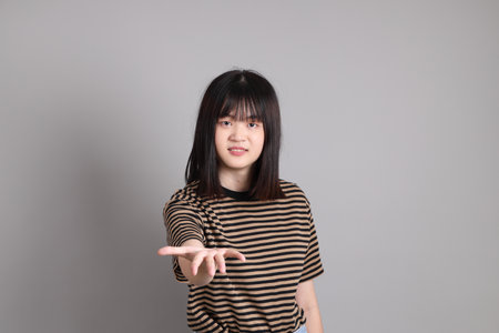 The young adult Asian woman standing on the grey backgroundの写真素材