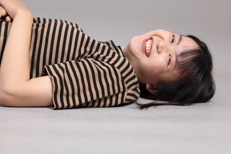 The yong adult Asian woman lying on the grey background.の写真素材