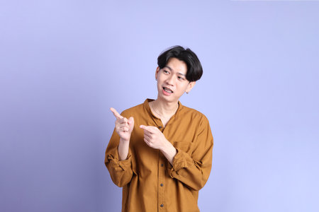 The Adult east Asian man with braces standing on the blue background.