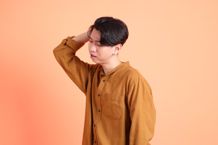 The Adult east Asian man with braces standing on the pink or orange background.