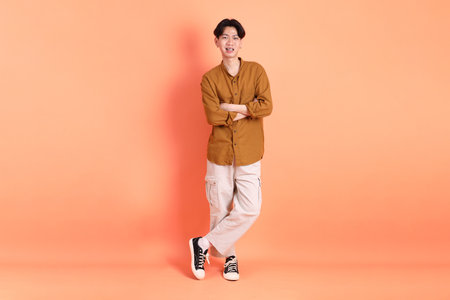 The Adult east Asian man with braces standing on the pink or orange background.