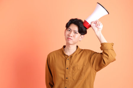 The Adult east Asian man with braces standing on the pink or orange background.の写真素材