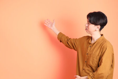 The Adult east Asian man with braces standing on the pink or orange background.の写真素材