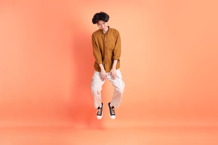 The Adult east Asian man with braces standing on the pink or orange background.の写真素材