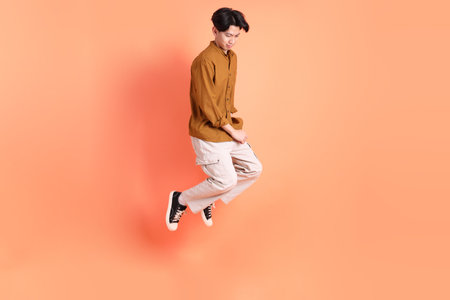 The Adult east Asian man with braces standing on the pink or orange background.の写真素材