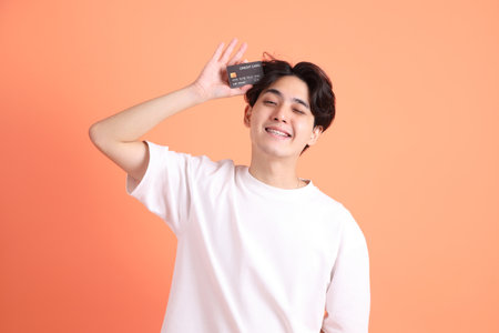 The Adult east Asian man with braces standing on the pink or orange background.